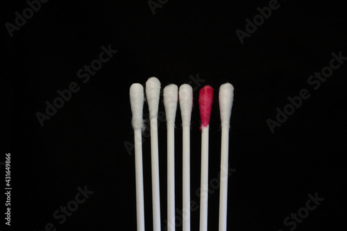 dare to be different six new white cotton buds isolated on a black background and one red
