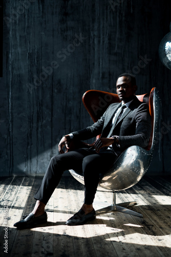 Handsome african american businessman sitting on a chair in the middle of a dark office