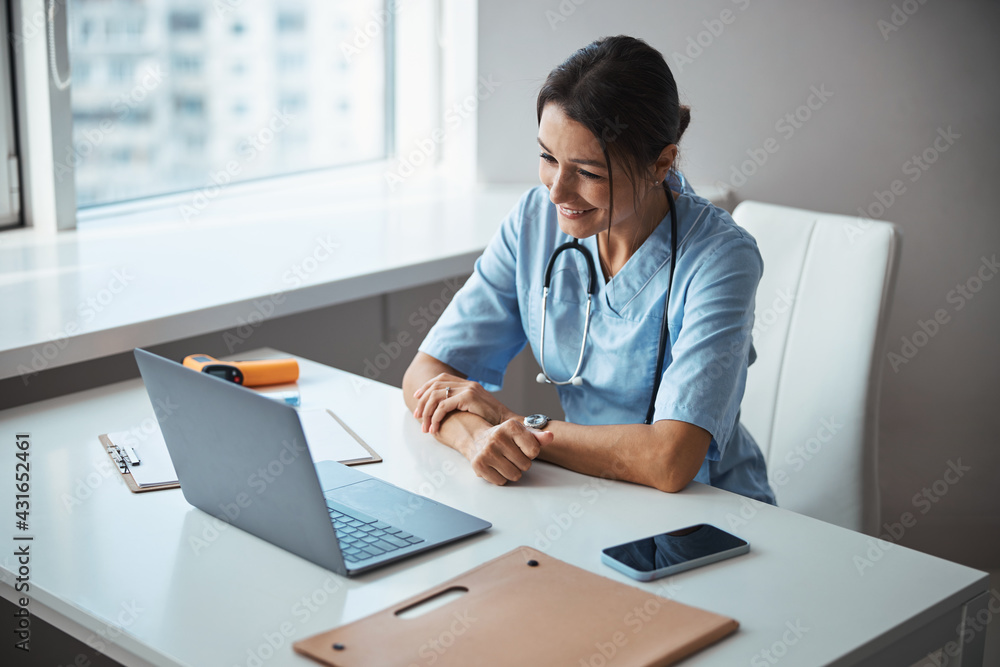 Joyful female doctor using modern laptop at work Joyful female doctor using modern laptop at work