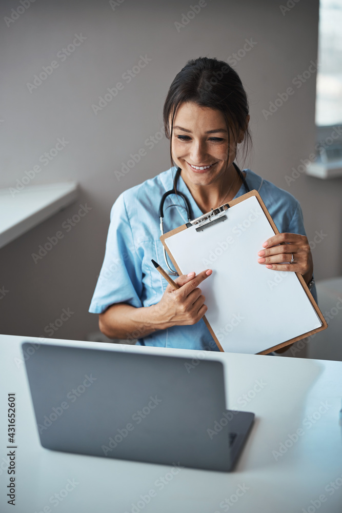 Joyful female doctor giving online consultation in clinic Joyful female doctor giving online consultation in clinic