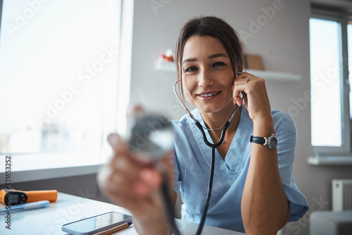 Cheerful female doctor using stethoscope in clinic