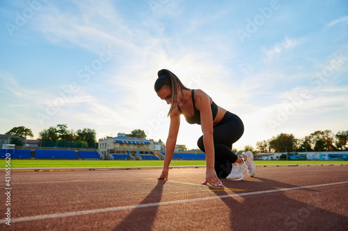 Young sport woman running at a track and field stadium © Vita