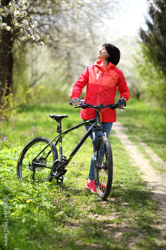 Beautiful woman on a bike in a blooming spring garden. Beautiful mature woman posing for the camera in a blooming spring garden.  © Master Video