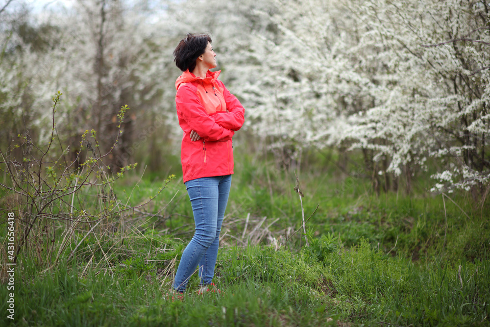 Beautiful mature woman posing for the camera in a blooming spring garden. 