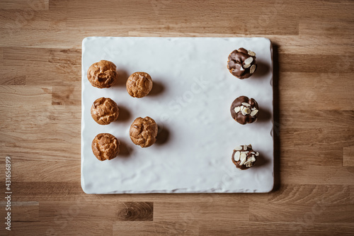 French eclairs or sweet Italian profiteroles on a wooden background