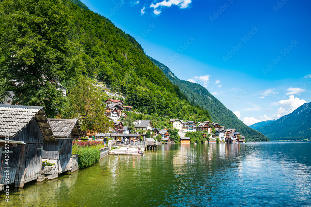 Naklejka premium Scenic view of famous Hallstatt lakeside town reflecting in Hallstattersee lake in the Austrian Alps on a sunny day in summer, Salzkammergut region, Austria