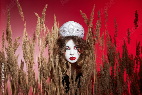 Fashion Russian woman in a kokoshnik with samovar on red background, bright makeup, make-up on woman face. Traditional Russian headdress, fashion modern style photo