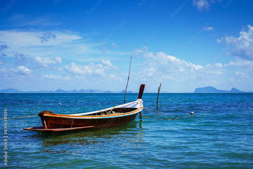 Old Thai wooden boats. Traditional tropical seascape. Traditional wooden longtail taxi boat. Fishing boat docked off the coast of the blue sea.