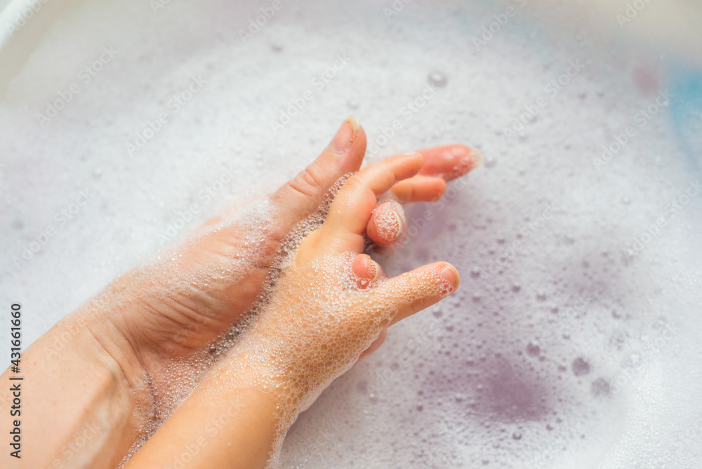 Women's and children's hands in white foam. Hygiene and cleanliness, skin care. High quality photo Women's and children's hands in white foam. Hygiene and cleanliness, skin care. High quality photo