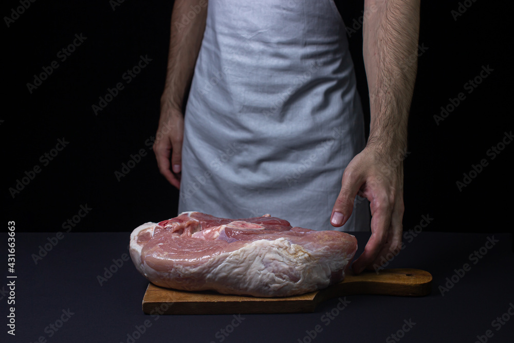Pork meat on a black background. Raw pork leg. Fresh raw meat. Chef holding a piece of meat on a dark background