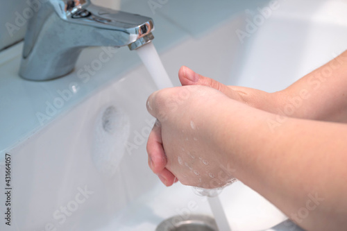 Two hands in the process of washing with soap on a blurry background with a sink. Wash your hands with soap and foam after a walk. Disinfection of hands from virus and dirt.