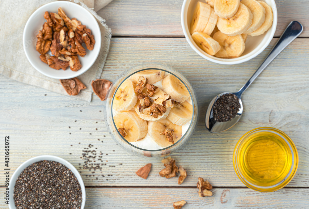 Banana cream pudding with chia seeds and nuts on a beige background. Top view. Banana cream pudding with chia seeds and nuts on a beige background. Top view.