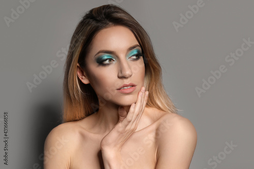 Young woman with evening makeup on grey background. Eye shadow product