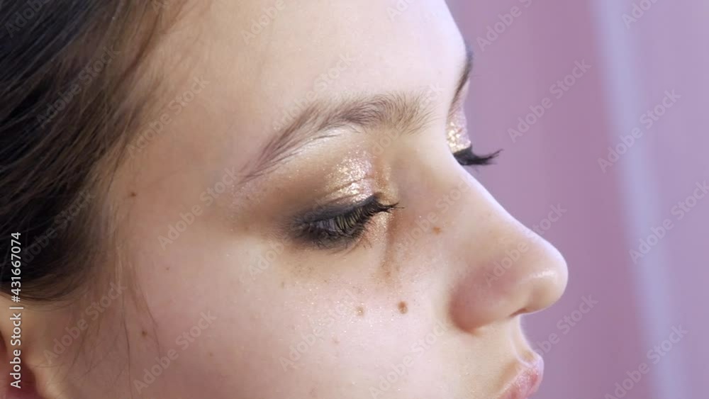 Brush applies mascara to beautiful young model's eyes for smoky eyes evening makeup Brush applies mascara to beautiful young model's eyes for smoky eyes evening makeup