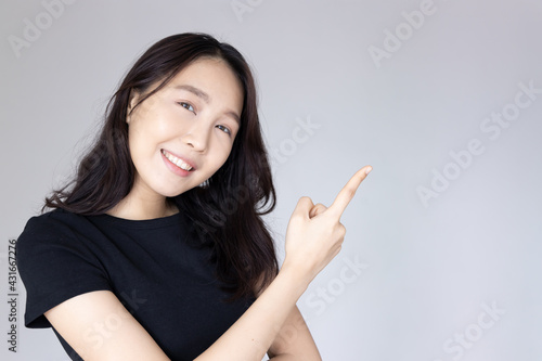Happy  smiling  confident asian young adult woman pointing to blank space