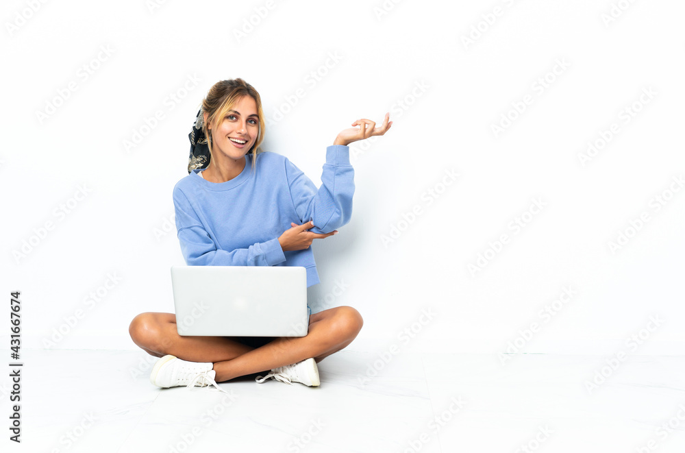 Young blonde Uruguayan girl with the laptop isolated on white background extending hands to the side for inviting to come Young blonde Uruguayan girl with the laptop isolated on white background extending hands to the side for inviting to come