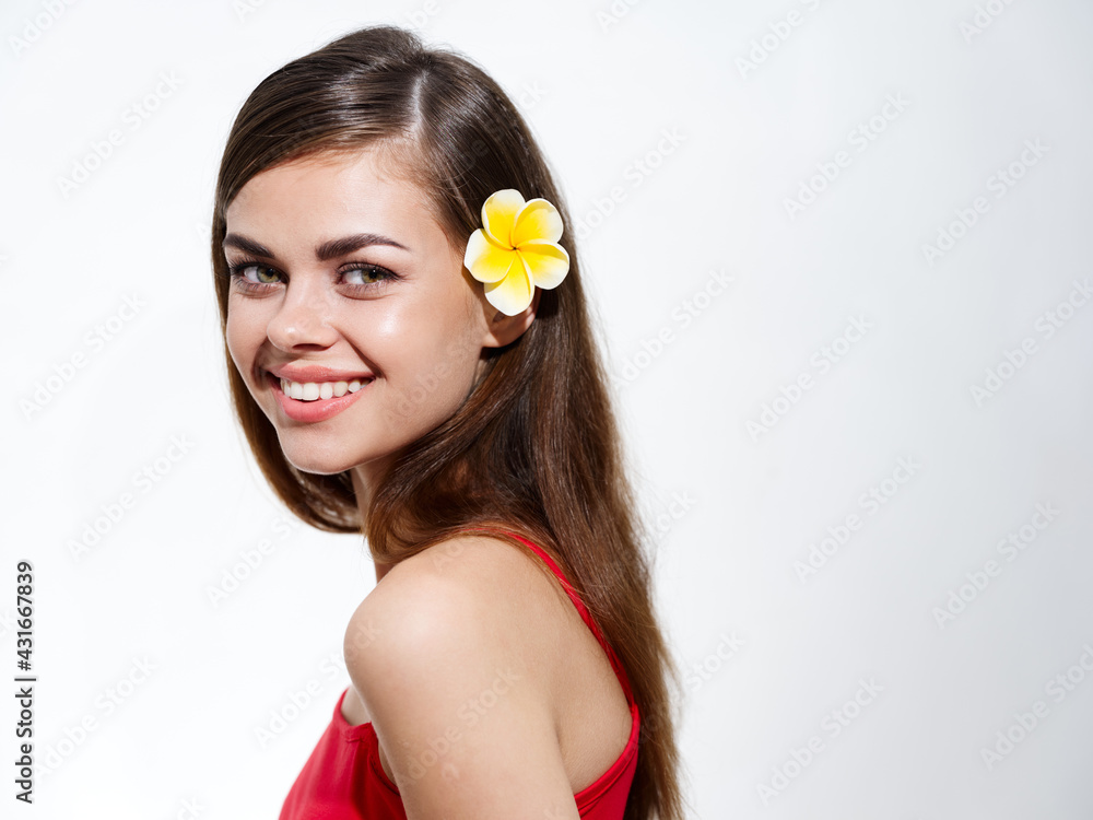 portrait of a happy woman with a yellow flower in her hair and in a red t-shirt brunette light background portrait of a happy woman with a yellow flower in her hair and in a red t-shirt brunette light background