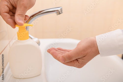 hand washing with soap or gel under running water in the washbasin  cleanliness and hygiene  men s hands dressed in a white shirt