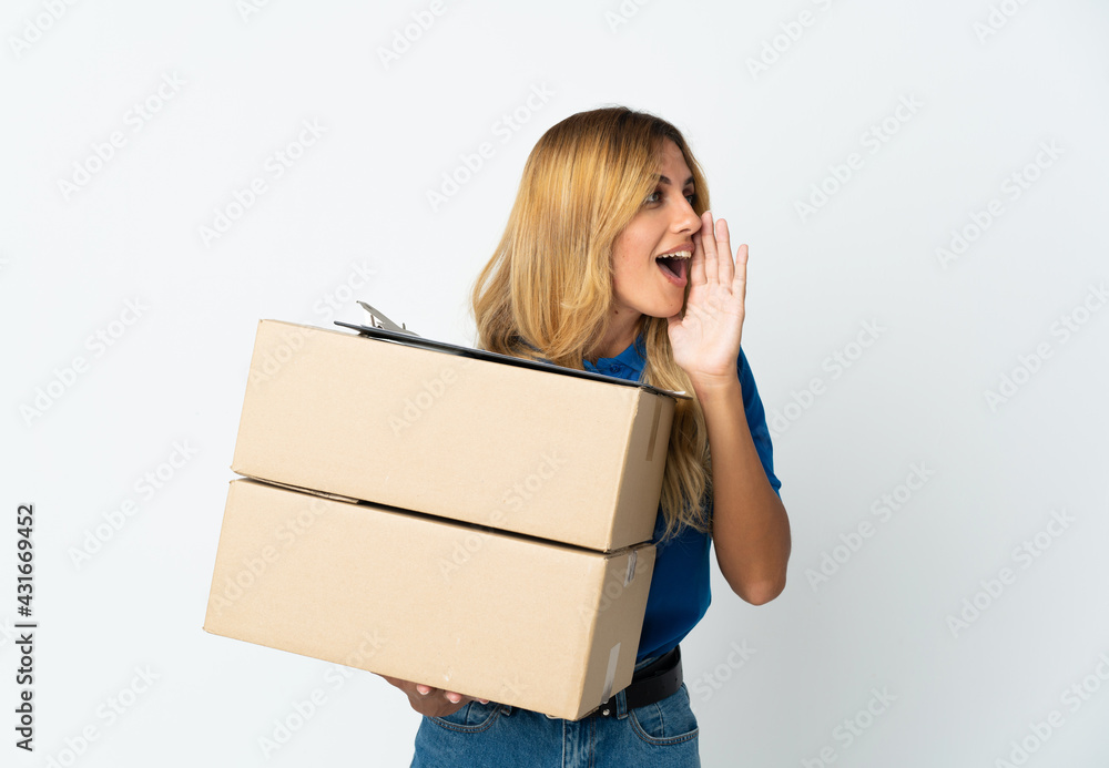 Young blonde Uruguayan delivery woman isolated on white background shouting with mouth wide open to the side Young blonde Uruguayan delivery woman isolated on white background shouting with mouth wide open to the side