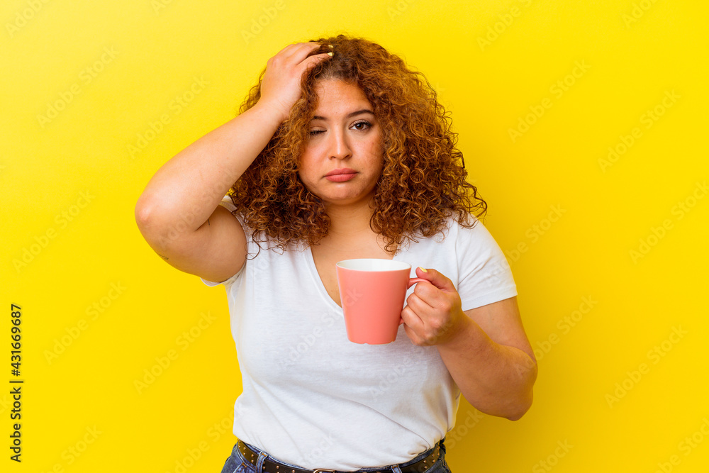 Young latin curvy woman holding a cup isolated on yellow background being shocked, she has remembered important meeting. Young latin curvy woman holding a cup isolated on yellow background being shocked, she has remembered important meeting.