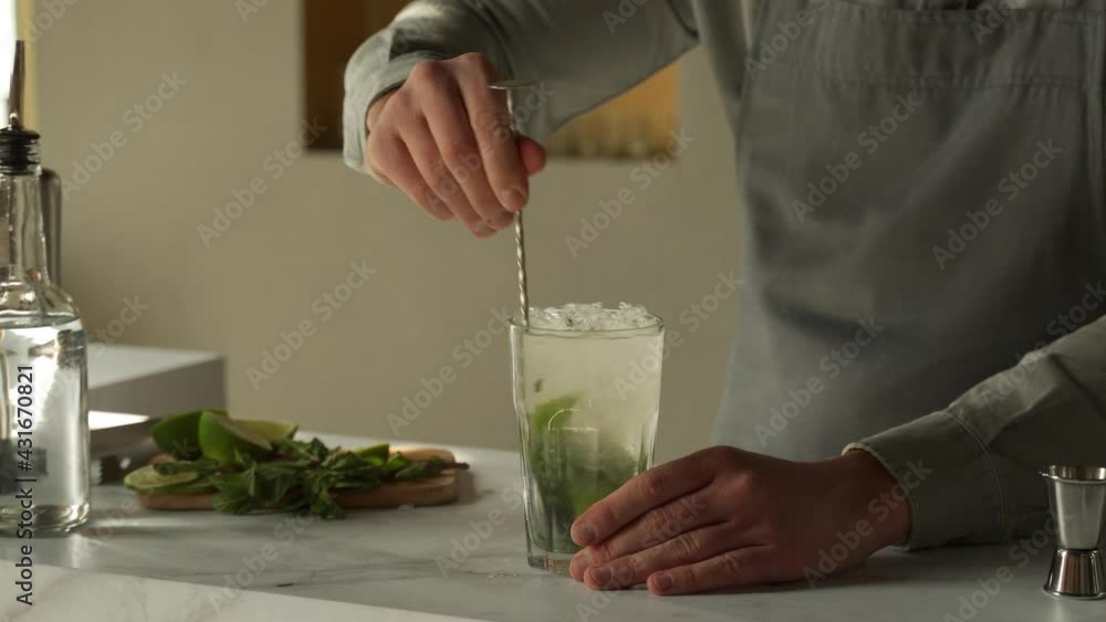 Bartender mixes an alcoholic mojito cocktail with a spoon Bartender mixes an alcoholic mojito cocktail with a spoon