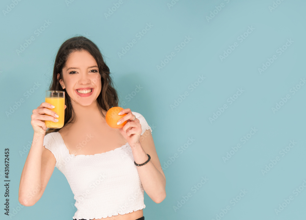 Caucasian woman with orange and orange juice isolated on blue Caucasian woman with orange and orange juice isolated on blue