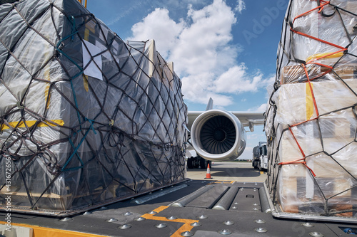 Preparation before flight. Loading of cargo containers against jet engine of freight airplane.  photo