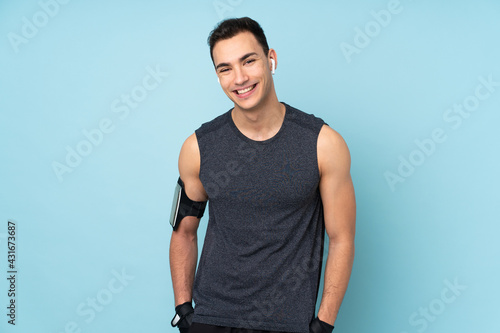 Young sport man over isolated on blue background happy and smiling © luismolinero