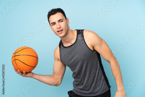 Man on isolated blue background playing basketball