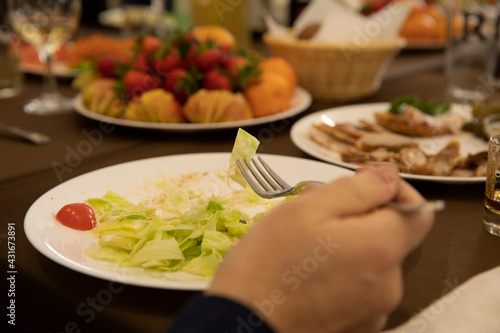 Man eating salad with fork from plate in restaurant