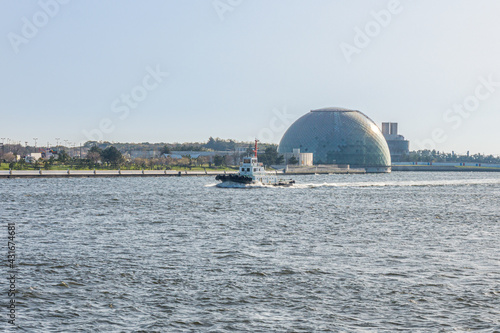 Boat running in front of Osaka Maritime Museum Dome. This area is located at Osaka bay in Japan. photo
