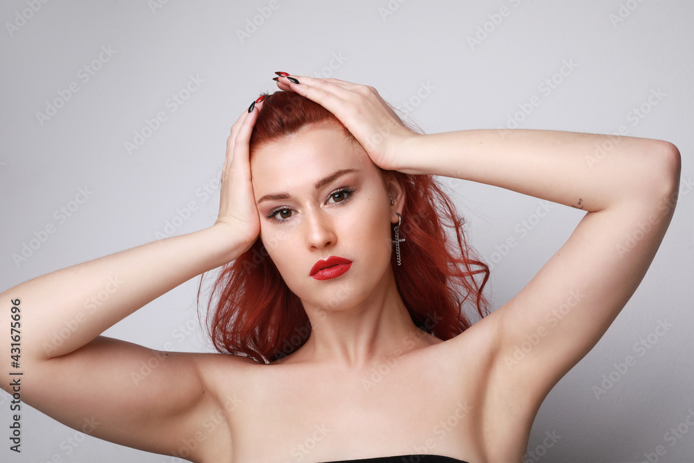 Naklejka premium Portrait of beautiful young woman with red hair posing over grey background. 