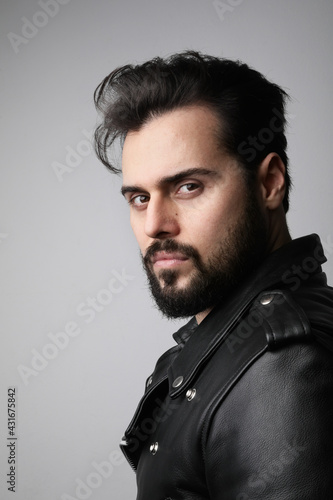 Vertical close-up portrait of young handsome bearded man, posing in the studio.