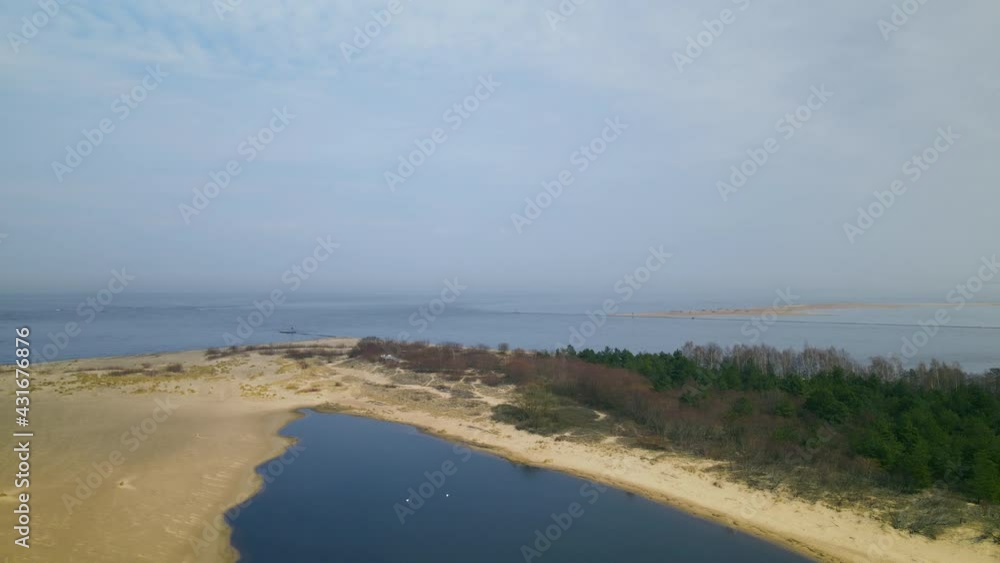 Aerial side shot of Mikoszewskie lake and Vistula River ended in sandbank of Mewia Lacha Nature Reserve during a sunny day, Baltic Sea in background. Aerial side shot of Mikoszewskie lake and Vistula River ended in sandbank of Mewia Lacha Nature Reserve during a sunny day, Baltic Sea in background.