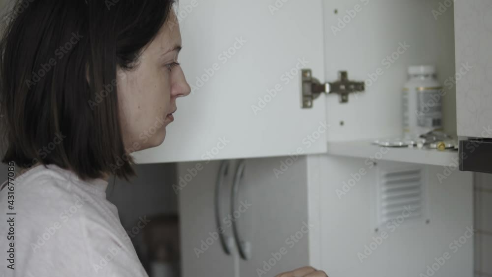 Close-up of woman open locker door in the kitchen to take her pills in the morning Close-up of woman open locker door in the kitchen to take her pills in the morning