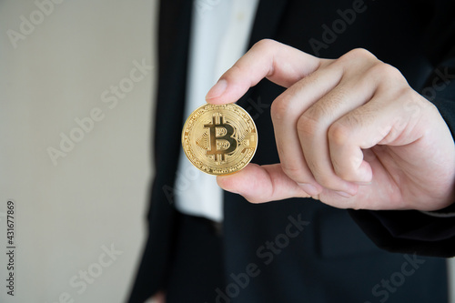 Unrecognizable businessman holding and showing a golden physical Bitcoin or BTC.