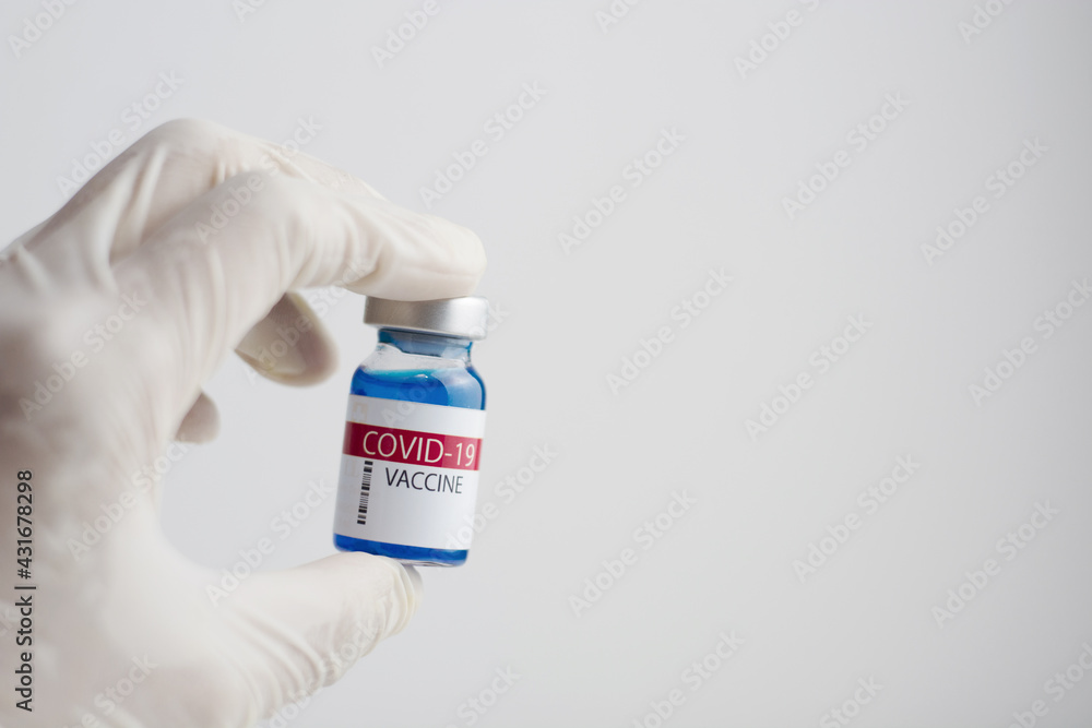 Hand wear glove holding Coronavirus vaccine bottle.Vaccination covid-19, medical research and development concept.