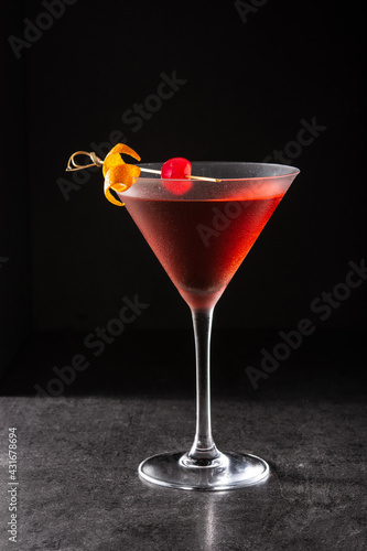 Traditional Manhattan cocktail with cherry on black background