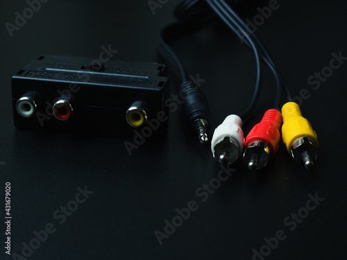 Audio-video adapter with plugs on dark background.
