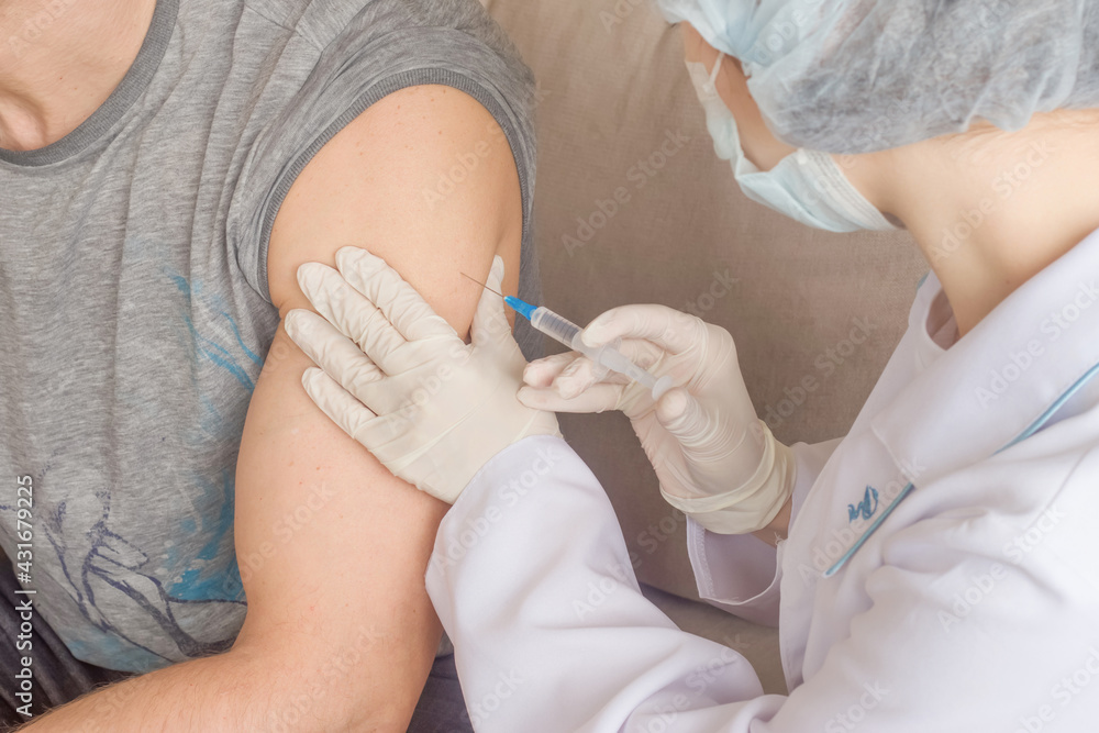 A nurse makes a vaccination to a man indoors A nurse makes a vaccination to a man indoors