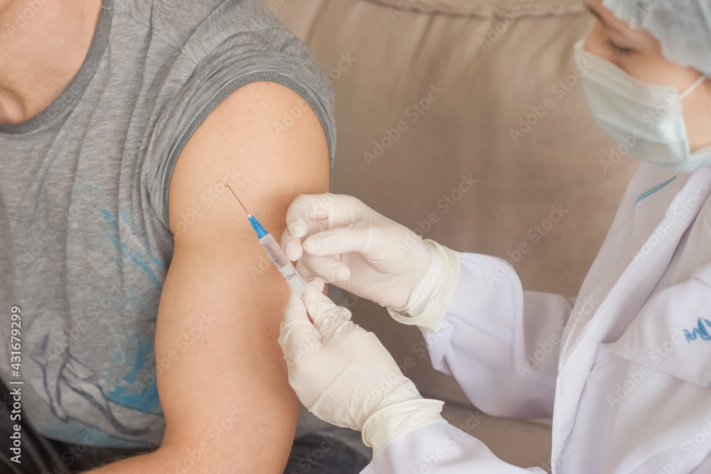 A nurse makes a vaccination to a man indoors A nurse makes a vaccination to a man indoors