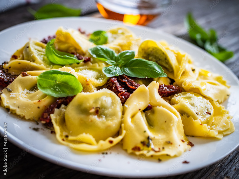 Tortelloni stuffed with ricotta cheese, basil pesto and vegetables on wooden table
Tortelloni stuffed with ricotta cheese, basil pesto and vegetables on wooden table