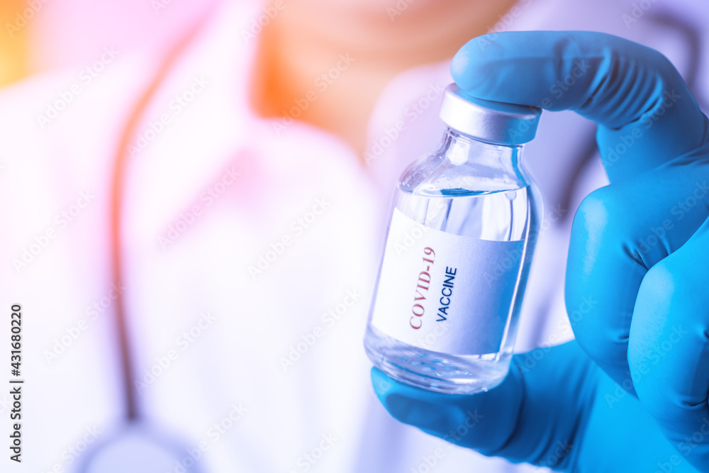 Obraz premium Doctor with a stethoscope on shoulder holding syringe and COVID-19 vaccine. Healthcare And Medical concept. Discovery Healing and End of Pandemic Living with COVID 19 Vaccine . Coronavirus Vaccine.