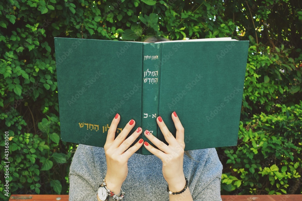 Girl with red nails reads the  hebrew book  - obrazy, fototapety, plakaty 
