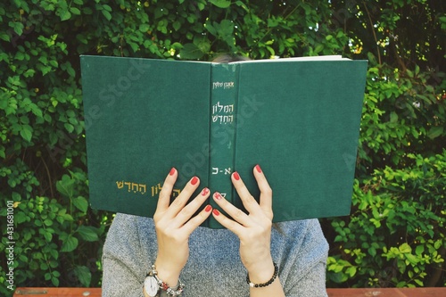 Foto Girl with red nails reads the  hebrew book