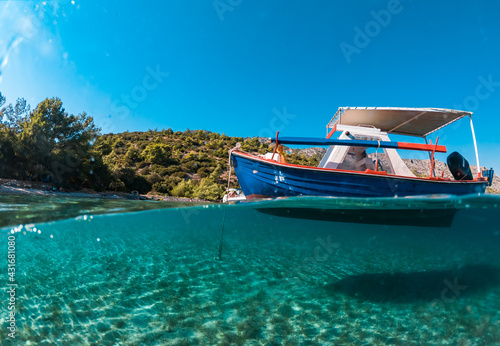 Half underwater photo of a boat in a beautiful beach of Samos island