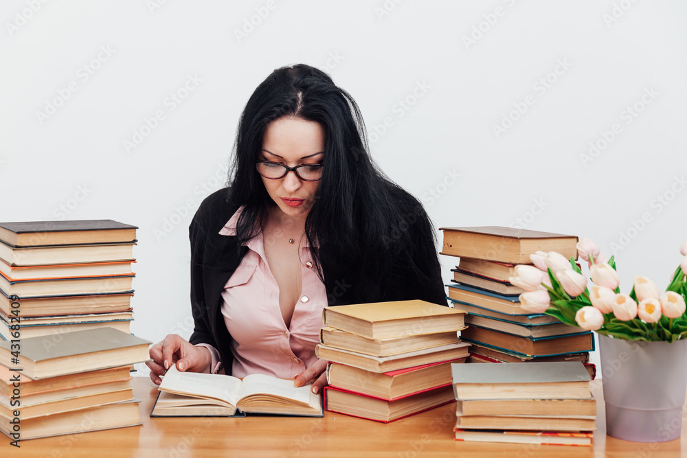 beautiful business woman in business suit at a table with stacks of educational books beautiful business woman in business suit at a table with stacks of educational books