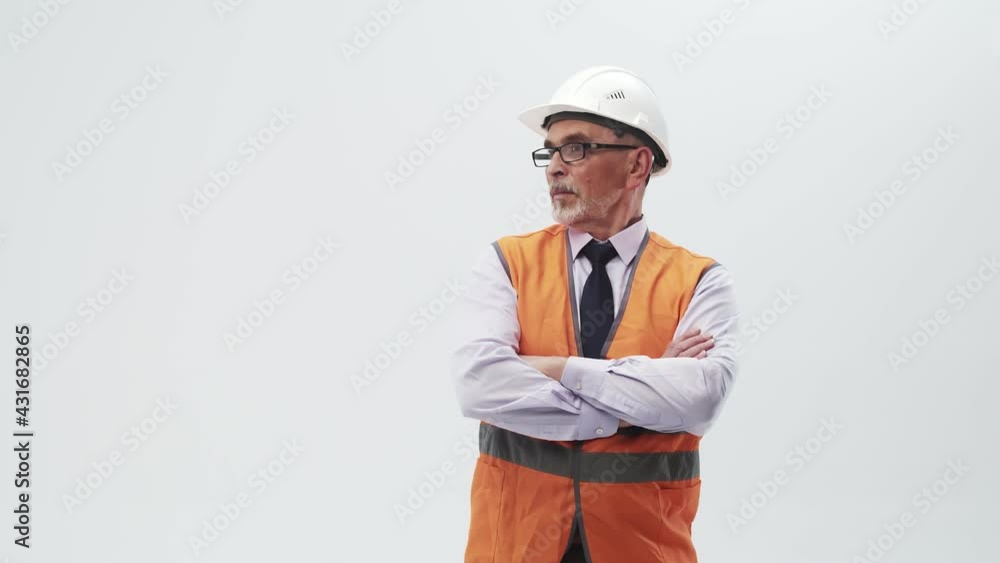 Adult man engineer in a working uniform and helmet puts hands on chest and looks to the side. Confident engineer crosses arms on chest in the studio a white background. Adult man engineer in a working uniform and helmet puts hands on chest and looks to the side. Confident engineer crosses arms on chest in the studio a white background.