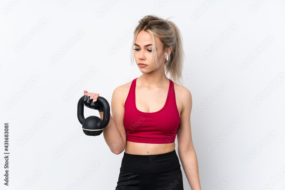 Teenager girl holding waffles over isolated blue background making weightlifting with kettlebell Teenager girl holding waffles over isolated blue background making weightlifting with kettlebell