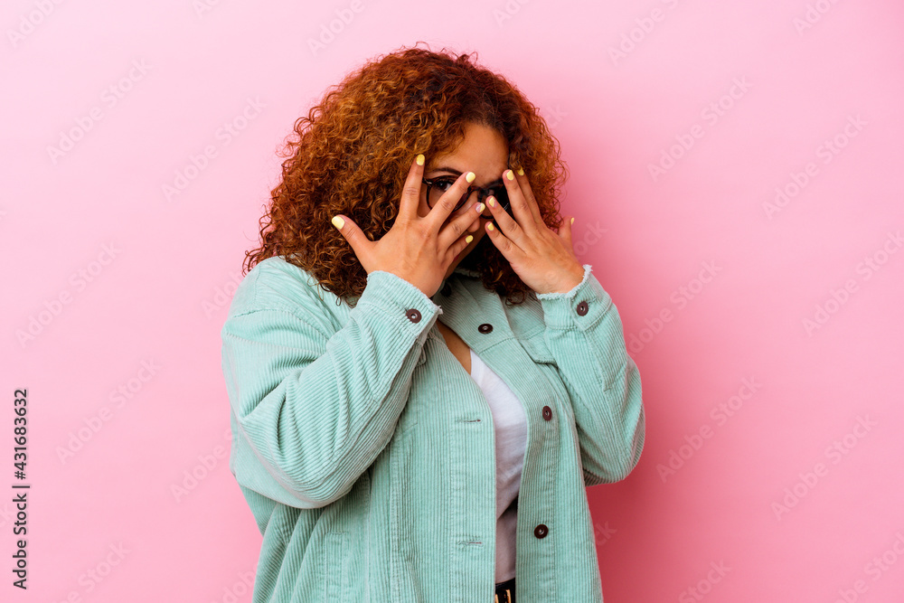 Young latin curvy woman isolated on pink background blink through fingers frightened and nervous. Young latin curvy woman isolated on pink background blink through fingers frightened and nervous.
